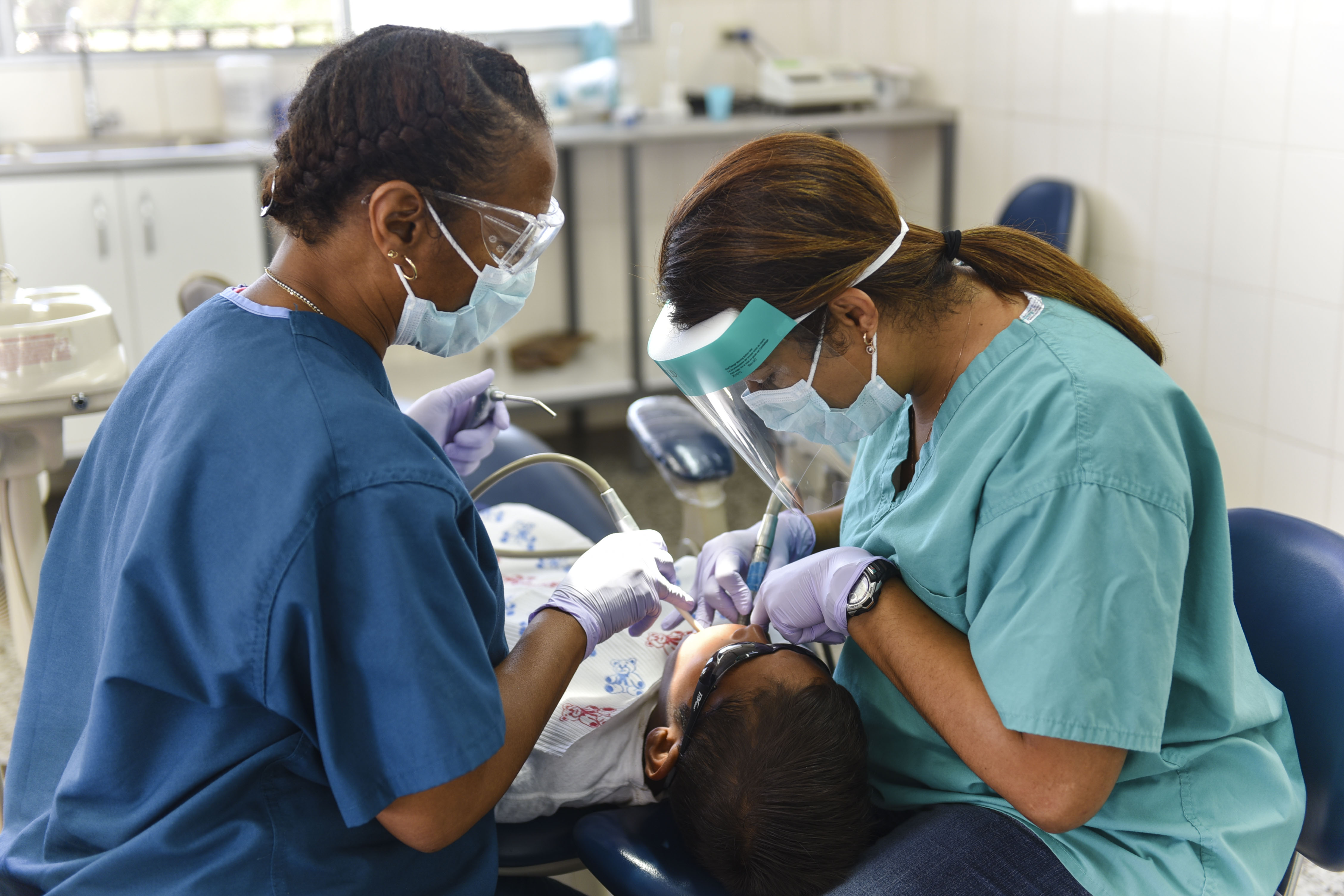 dentist and dental assistant giving treatment to a child while wearing PPE
