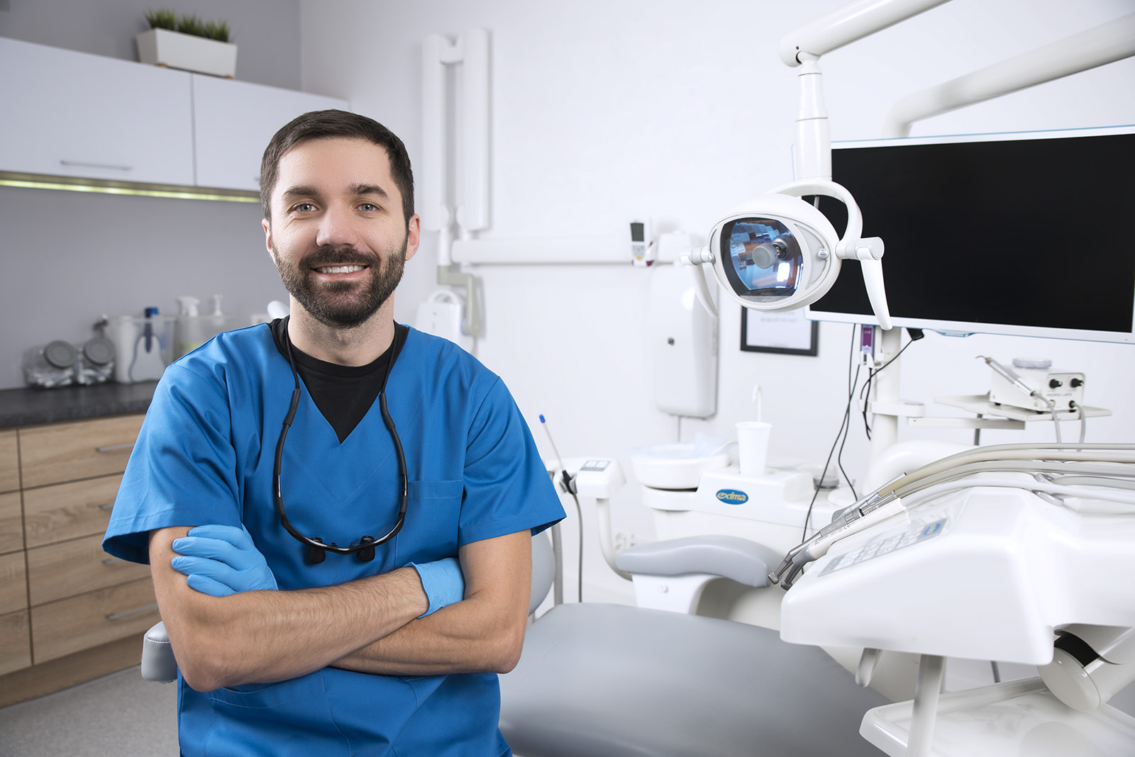 Dentist With Arms Folded In Front Of Dentists Chair 