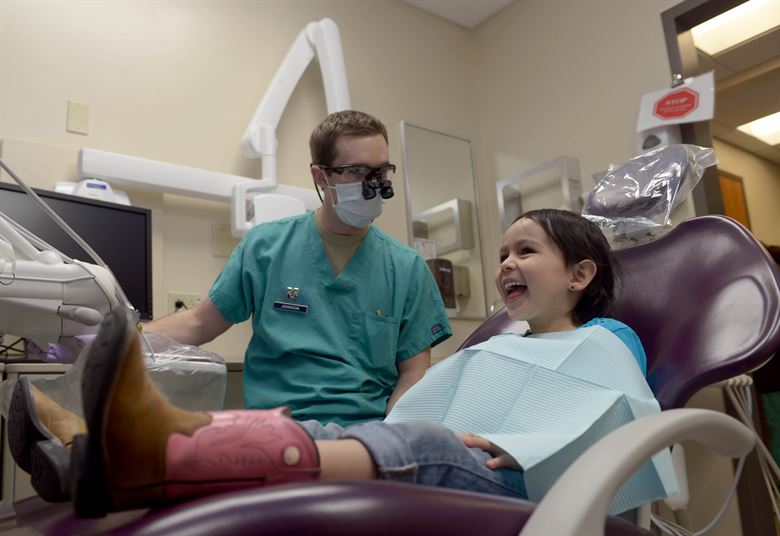pediatric dentist starting an exam with a young girl in the dentist's chair