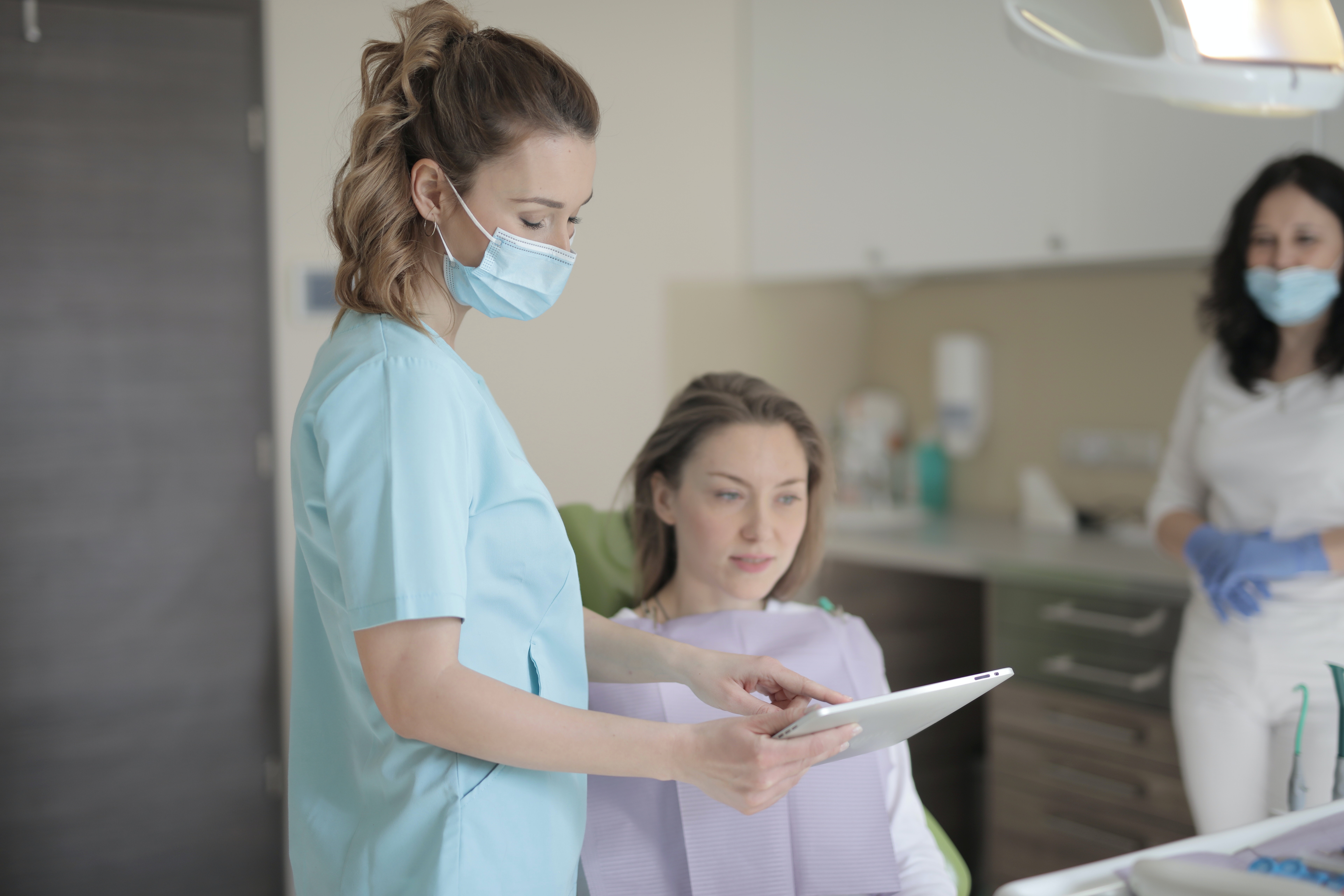 Dental assistant showing female patient payment options with CareCredit on an iPad