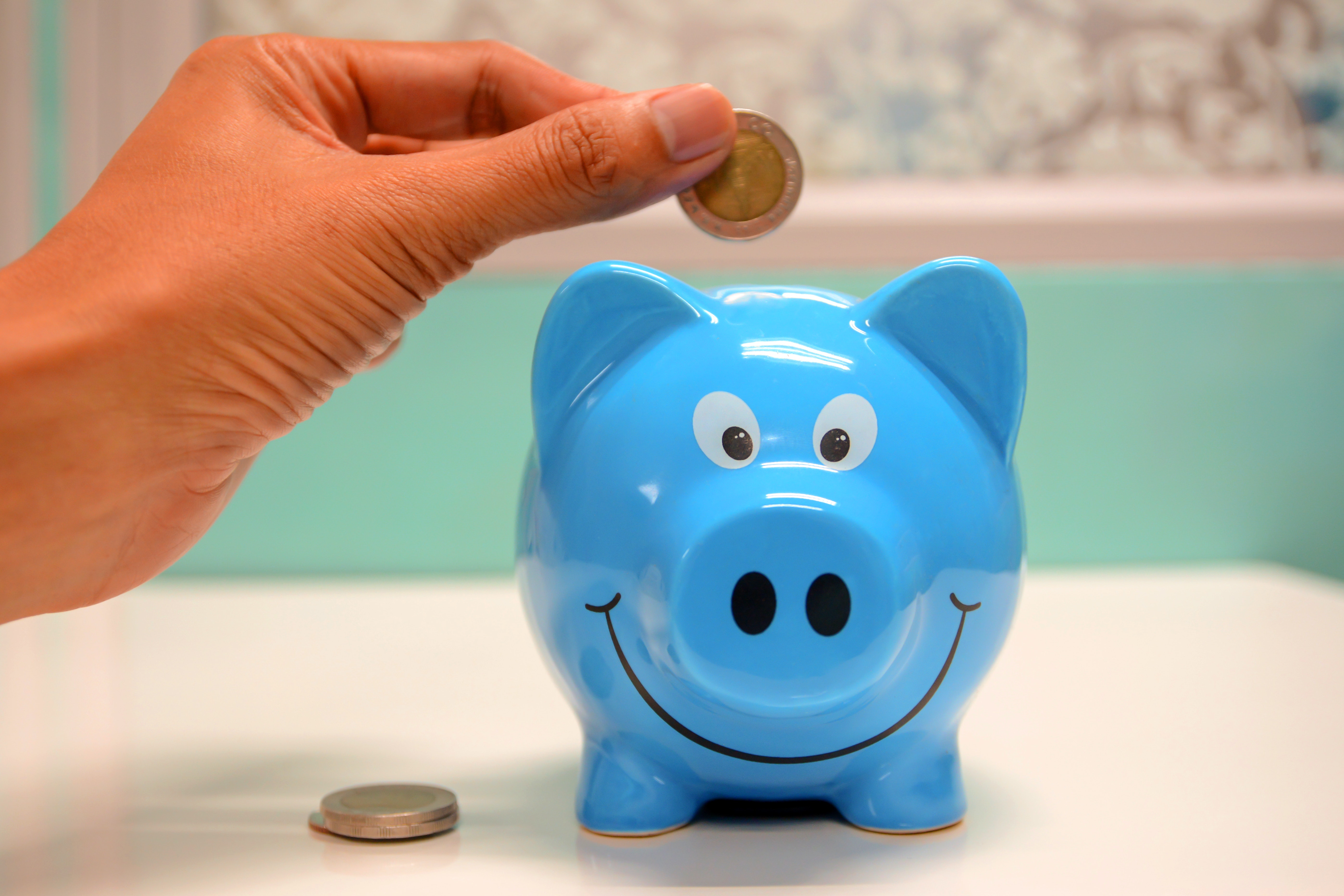 Putting money in a piggy bank to save up for teeth whitening