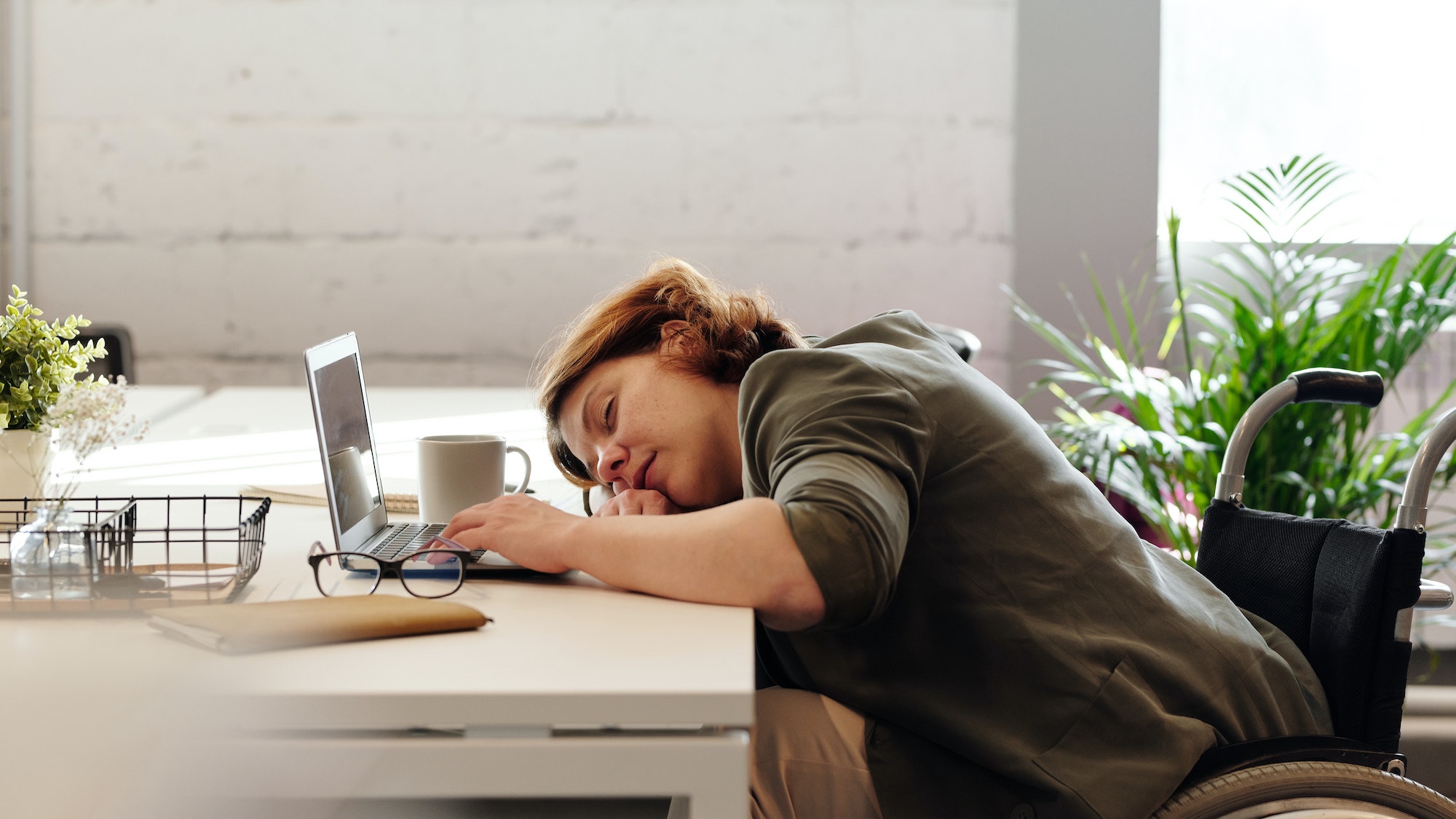 Woman asleep at her laptop after getting bad sleep due to teeth grinding at night