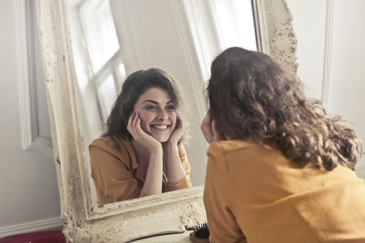 woman checking out teeth whitening in mirror